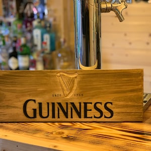 May include: A wooden sign with the Guinness logo and the text "ESTD 1759 GUINNESS".