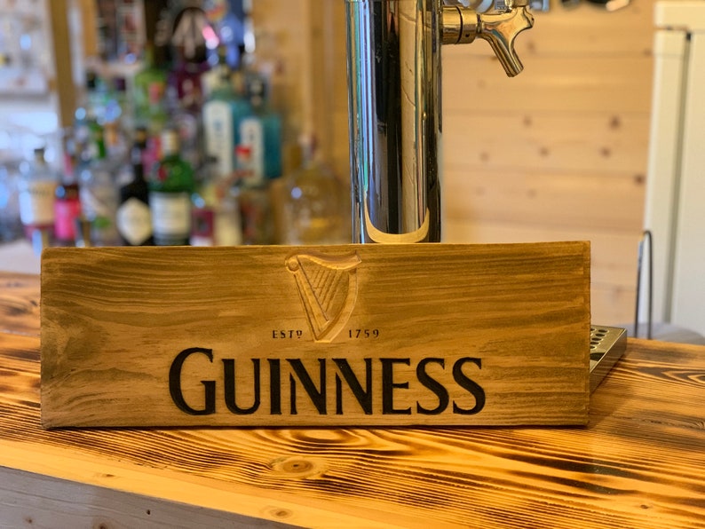 May include: A wooden sign with the Guinness logo and the text "ESTD 1759 GUINNESS".