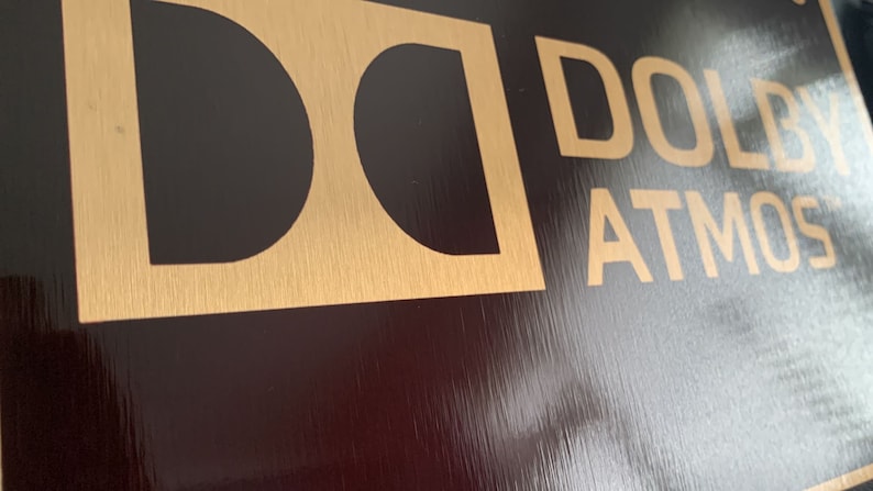 May include: A gold and black sign with the text "Dolby Atmos" in gold lettering.