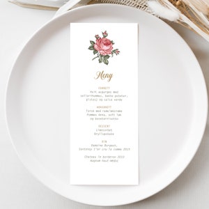 May include: A white menu card with a pink rose illustration and gold text. The menu includes a three-course meal: white asparagus with celery hummus, baked potatoes, pistachios, and salsa verde; cod with ramsløk cream, pommes Anna, soft cod, and buckwheat risotto; and lime sorbet and wedding cake. The wine pairings are Domaine Borgeat Santenay l'er cru la comme 2015 and Chateau le borderon 2010 magnum haut-médoc.