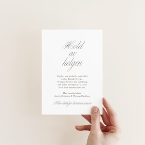 May include: A white wedding announcement card with black text. The card reads "Hold av helgen" which translates to "Save the weekend" in English. The card also includes the date and location of the wedding, as well as the names of the couple.