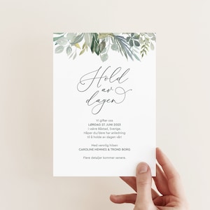 Puede incluir: Una tarjeta blanca de guardar la fecha con follaje verde acuarela en la parte superior. El texto dice "Hold av dagen" en escritura cursiva negra. El texto debajo dice "Vi gifter oss LØRDAG 27. JUNI 2023 i vakre Båstad, Sverige. Håper du/dere har anledning til å holde av dagen vår! Med vennlig hilsen CAROLINE HEMNES & TROND BORG Flere detaljer kommer senere."