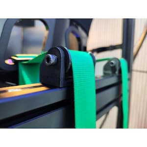 Può includere: Primo piano di un componente nero stampato in 3D con una cinghia verde brillante. Il componente è fissato a un telaio metallico nero. Il testo "FastPrint3D" è visibile sul componente.