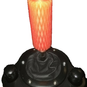 Può includere: Un pomello del cambio auto personalizzato con un design geometrico a reticolo nelle tonalità dell'arancione e del giallo. Il pomello è posizionato sopra un rivestimento del cambio in pelle nera e una console nera con dettagli argentati.