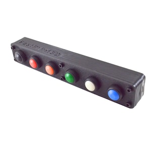 May include: A black rectangular device with six multi-colored buttons. The buttons are black, red, orange, green, white, and blue. The text "FastPrint3D" is embossed on the top of the device.
