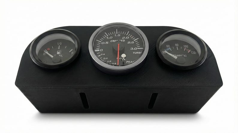 May include: A black dashboard gauge pod with three circular gauges. The center gauge reads up to 3.0, with a red needle. The left gauge shows a fuel level, and the right gauge displays temperature in Celsius.