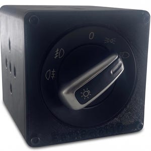 K&ouml;nnte beinhalten: Ein schwarzer Autoscheinwerferschalter mit einem silbernen Bedienknopf. Der Schalter hat Markierungen f&uuml;r verschiedene Lichteinstellungen, einschlie&szlig;lich Scheinwerfer und Nebelscheinwerfer. Der Schalter ist in einem quadratischen Geh&auml;use montiert.