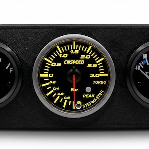 May include: A black dashboard gauge cluster with three circular gauges. The left gauge shows fuel level, the center gauge reads "CNSPEED" and "TURBO", and the right gauge displays temperature in Celsius. The gauges have yellow illumination.