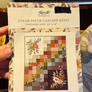 May include: A quilt pattern booklet titled Color Patch Cascade Quilt by Fancy That Design House Co. The cover features a finished size of 44 inches by 56 inches and displays a patchwork quilt design with floral illustrations and small squares.