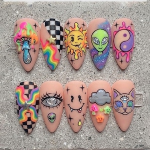 May include: A set of ten almond-shaped press-on nails featuring a nude base with colorful hand-painted designs including a melting mushroom, rainbow checkerboard, winking sun, alien head, yin-yang, eye, smiley face, cloud, and a three-eyed cat.