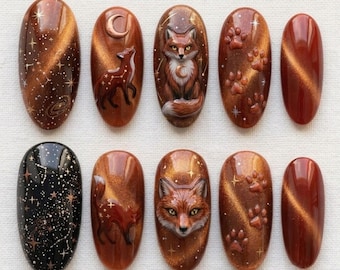 Puede incluir: Un juego de diez uñas postizas ovaladas con acabado brillante. Los diseños incluyen una uña negra con estrellas doradas, varias uñas marrones con efecto ojo de gato, ilustraciones de zorros, lunas crecientes y huellas en 3D.
