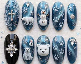Puede incluir: Un juego de diez uñas postizas con temática invernal. Nueve uñas son de color azul oscuro brillante con copos de nieve plateados, figuras de osos polares blancos, muñecos de nieve y huellas. Una uña es negra con una estrella de cristal facetada.