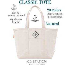 May include: A natural-colored canvas tote bag with a monogrammed design. The bag features a zip closure and key fob. Text on the image reads "CLASSIC TOTE", "20 Colors", "heavy canvas", "medium/large", and "Natural".