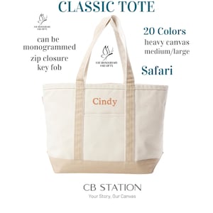 May include: A canvas tote bag in a cream color with tan accents. The bag has a zip closure, key fob, and can be monogrammed. The text "Cindy" is embroidered on the front. The words "Classic Tote", "20 Colors", and "Safari" are also visible.