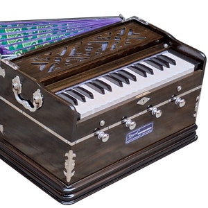 May include: A dark brown wooden harmonium with a white keyboard and bellows. The harmonium has a decorative design on the front and a silver label that reads "Super Sound Harmonium".