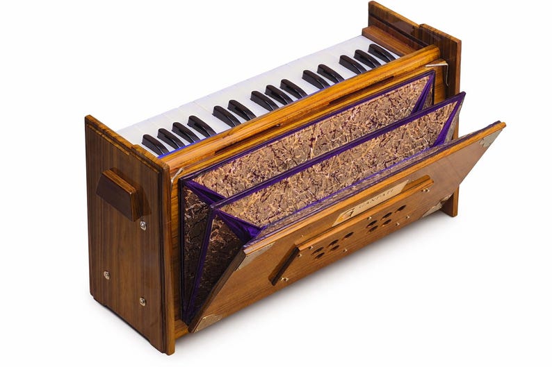Pode incluir: Um harm&oacute;nio de madeira com um teclado de teclas brancas e pretas. O instrumento tem um exterior castanho com pain&eacute;is decorativos e acabamentos roxos. O fole est&aacute; parcialmente aberto, revelando a estrutura interna.