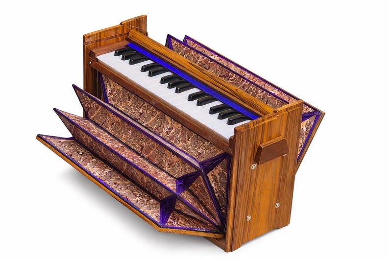 Pode incluir: Um harm&oacute;nio de madeira com um teclado de teclas brancas e pretas. O instrumento tem um fole com padr&atilde;o castanho e roxo e um detalhe azul acima das teclas. A estrutura de madeira tem um gr&atilde;o de madeira natural.