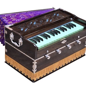 May include: A dark brown wooden harmonium with a light green keyboard and a purple bellows. The harmonium has decorative silver accents and a carved wooden design on the top.