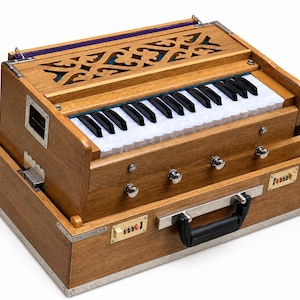 May include: A wooden harmonium with a keyboard, silver accents, and a black handle. The instrument has a decorative top with carved patterns and a small metal plate with the text "Tossie". The harmonium is a musical instrument.