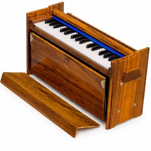 Pode incluir: Um harm&oacute;nio de madeira com acabamento brilhante. O instrumento apresenta um teclado com teclas pretas e brancas, um detalhe azul e um painel de madeira remov&iacute;vel. O harm&oacute;nio foi concebido para atua&ccedil;&atilde;o musical.