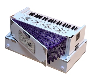 May include: A white harmonium with a purple bellows and a silver nameplate that reads "GANPATI".