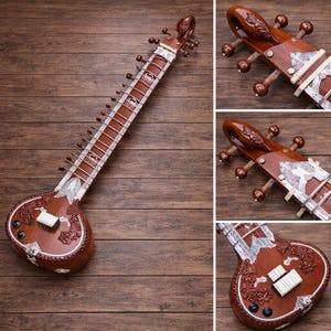 May include: A brown sitar, a traditional Indian stringed instrument, rests on a wooden surface. The sitar features intricate carvings, decorative silver-colored accents, and multiple strings. The instrument's body has a rounded shape, and the neck is long and slender.