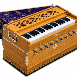 May include: A wooden harmonium musical instrument featuring a keyboard with black and white keys, a bellows system with purple fabric, silver-toned metal hardware, and a decorative carved wooden panel covering the top section of the instrument.