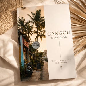 Könnte beinhalten: Ein Reiseführer mit dem Titel "CANGGU" und dem Untertitel "The Ultimate Guide to Paradise". Das Cover zeigt eine Straßenszene mit Palmen und einem Roller. Das Buch liegt auf einer beigen Oberfläche.