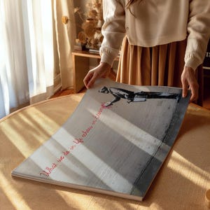May include: A white canvas print featuring a black and white image of a person spray painting a wall. The text "What we do in life echoes in eternity" is written in pink across the bottom of the print.