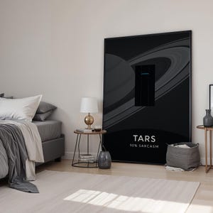 May include: A large black framed poster with a graphic of a planet and rings, with the text "TARS 90% SARCASM". The poster is in a bedroom with a bed, side tables, and a lamp.