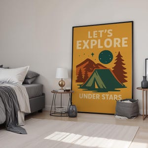 May include: A framed poster with a camping theme. The poster has a mustard yellow background with the words "LET'S EXPLORE UNDER STARS". The illustration features a green tent, brown trees, mountains, a moon, and stars.
