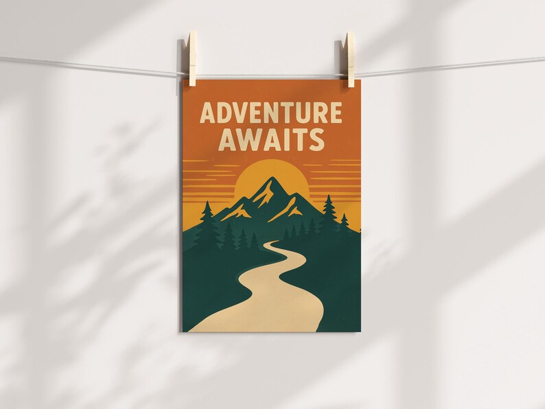 May include: A rectangular poster with the words "ADVENTURE AWAITS" in white block letters. The poster features a mountain range, a setting sun, and a winding road in shades of green, orange, and beige. The poster is hanging from a clothesline with wooden clips.