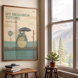 Może przedstawiać: Oprawiony plakat z filmu "Mój sąsiad Totoro" w drewnianej ramie. Grafika przedstawia Totoro z parasolem na przystanku autobusowym, z japońskim tekstem. Plakat ma styl vintage i stonowaną paletę barw.