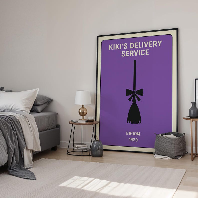 Puede incluir: Un p&oacute;ster enmarcado con fondo morado muestra el texto "KIKI'S DELIVERY SERVICE" y una ilustraci&oacute;n de escoba negra. Las palabras "BROOM 1989" est&aacute;n debajo de la escoba. El p&oacute;ster est&aacute; en un dormitorio con una cama, mesitas de noche y una alfombra.