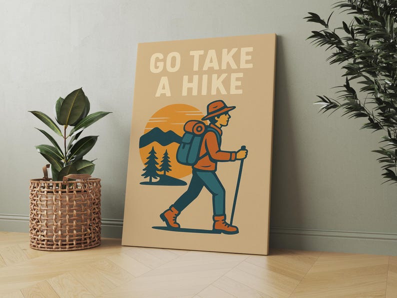 May include: Tan canvas art print with the words "GO TAKE A HIKE" above an illustration of a hiker with a backpack, walking stick, and hat. The background features a sunset, mountains, and pine trees.