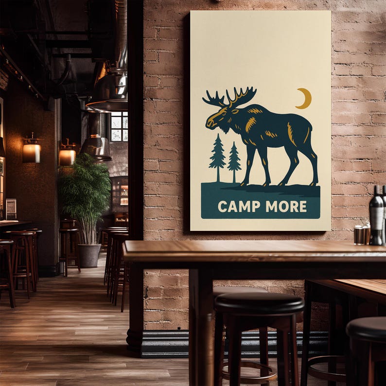 May include: A rectangular canvas print featuring a stylized moose illustration in navy blue and gold against a cream background. Two green pine trees and a gold crescent moon are also depicted. The text "CAMP MORE" is displayed in a navy blue banner.