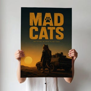 Op de afbeelding: Poster met de woorden "MAD CATS" in grote, verweerde oranje letters, met een pootafdruk ter vervanging van de "O". Daaronder staat de tekst "THE FUTURE BELONGS TO THE FERAL". Een illustratie van een katachtig figuur in harnas staat voor een voertuig.