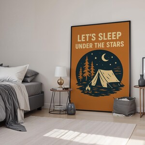 May include: A framed poster with the text "LET'S SLEEP UNDER THE STARS" above a camping scene. The illustration features a tent, trees, a campfire, a crescent moon, and stars, set against a dark blue circle on an orange background.