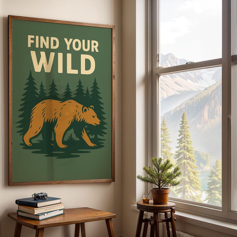 May include: A framed poster with the text "FIND YOUR WILD" above a bear illustration. The bear is walking in front of a forest of green trees. The poster is in a room with a window overlooking a mountain range.