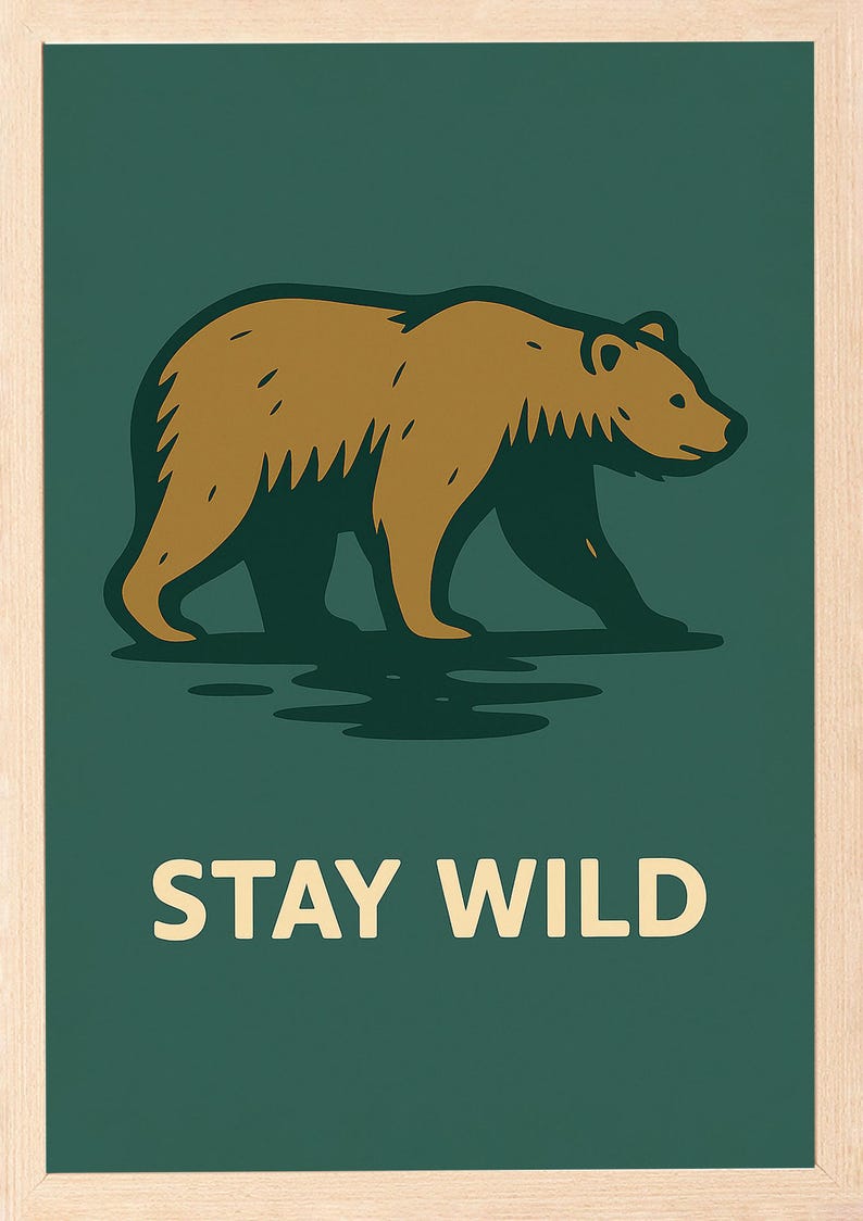 May include: A framed print with a brown bear illustration on a dark green background. The text "STAY WILD" is displayed in white block letters. The artwork has a minimalist style and evokes a sense of the outdoors.