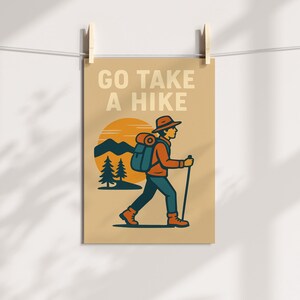 May include: Tan poster with the text "GO TAKE A HIKE" above an illustration of a hiker. The hiker is wearing a hat, backpack, and hiking boots, and is walking with a walking stick. The background features a sunset, mountains, and pine trees.