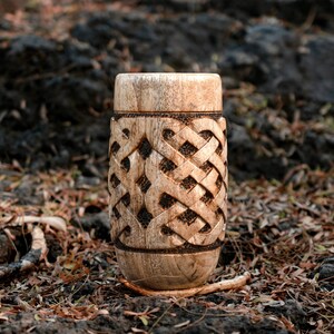May include: A wooden cup with a carved Celtic knot design. The cup is brown and has a natural wood finish.
