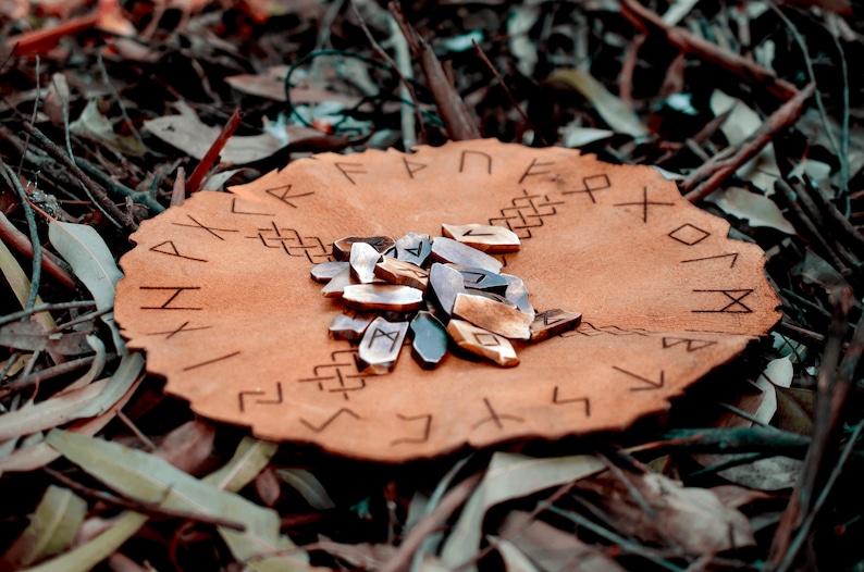 Pu&ograve; includere: Una sacca di cuoio con rune incise sulla superficie. Un mucchio di rune di legno si trova al centro della sacca.