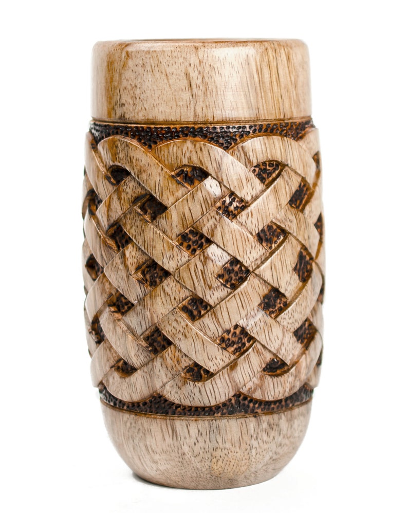 May include: A wooden vase with a carved Celtic knot design. The vase is light brown with dark brown accents.