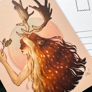 Op de afbeelding: Ansichtkaart met een illustratie van een vrouw met geweien en lang, vloeiend haar. Het haar loopt over van blond naar bruin met witte vlekken. Ze houdt een eikenblad en een eikel vast. De achtergrond heeft een zachte roze cirkel.