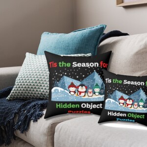 Könnte beinhalten: Zwei schwarze Kissen mit weißen und bunten Pinguin-Illustrationen. Die Kissen haben den Text "Tis the Season for Hidden Object Puzzles" aufgedruckt.