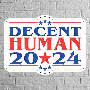 May include: A white sign with red and blue text and stars. The sign says "DECENT HUMAN 20*24".