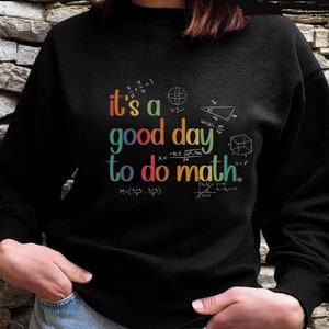 May include: Black sweatshirt with the text "it's a good day to do math" in colorful lettering. The design includes math symbols and equations. The sweatshirt is a crew neck style.