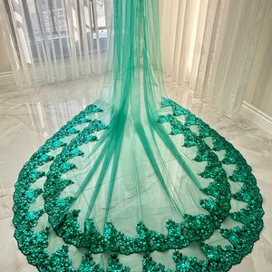 May include: A teal green tulle veil with a scalloped edge and a double layer of emerald green sequin trim.