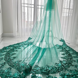 May include: A teal bridal veil with a sequined lace trim. The veil is made of soft tulle and is perfect for a wedding.